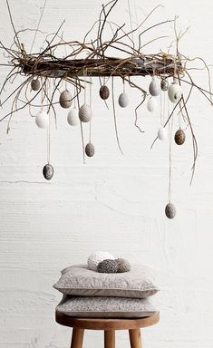 a wooden stool sitting under a tree branch filled with balls and ornaments hanging from it's branches