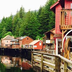 a wooden dock with houses on the water and trees in the backgrouds