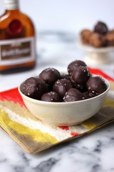 a white bowl filled with chocolate covered donuts on top of a table next to a bottle