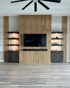 a living room with wood paneling and ceiling fan in the center, along with built - in shelving