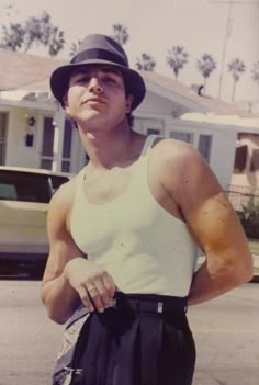 a young man wearing a hat standing in front of a house