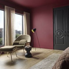 a bedroom with red walls and furniture in front of a large window, next to a bed