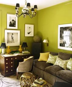 a living room with green walls and pictures on the wall, furniture in front of it