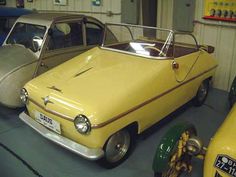 an old yellow car is parked in a garage