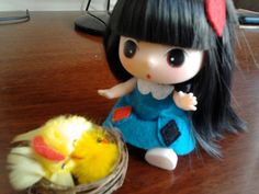 a small doll sitting next to a yellow bird