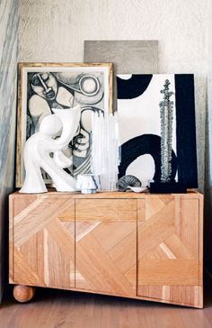 a wooden cabinet with art on top of it