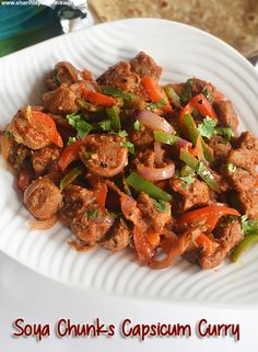 a white plate topped with meat and veggies next to a pita bread