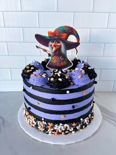 a blue and black striped cake with an image of a witch on top