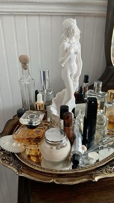 an assortment of perfumes on a tray with a statue in the corner behind it