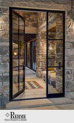 an open glass door leading into a stone building