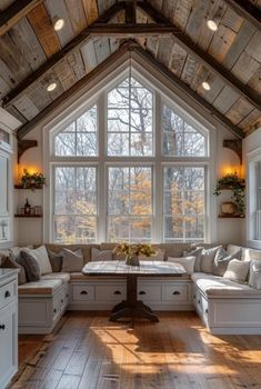 a living room filled with lots of furniture under a large window on top of a wooden floor