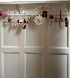 christmas decorations hanging from the ceiling in front of a white paneled door with wooden slats