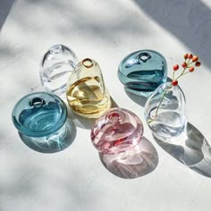 four glass vases sitting on top of a white surface