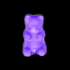 a purple teddy bear sitting in the dark