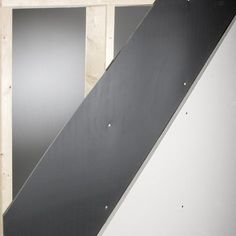 a black skateboard leaning against the wall in a room with unfinished walls behind it