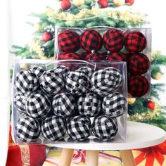 black and white buffalo plaid christmas balls in clear plastic boxes on a table next to a christmas tree