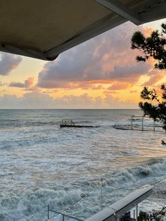 the sun is setting over the ocean with boats in the water