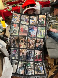 a man sitting on a couch holding up a quilt with pictures of people all over it