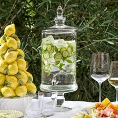 a table topped with plates and glasses filled with food next to a tall glass container