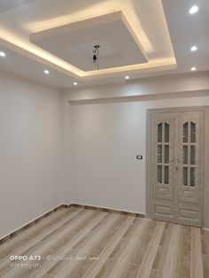 an empty room with wooden floors and white walls, lights on the ceiling and doors