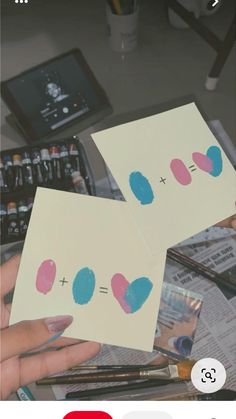 two pieces of paper with blue and pink dots on them are being held by someone's hands