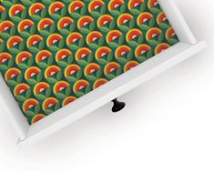 an image of a green and orange pattern on a white box with black knobs