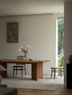 a dining room table with two chairs and a vase filled with flowers on top of it