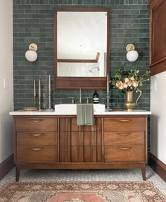 a bathroom with green tile and wooden cabinets