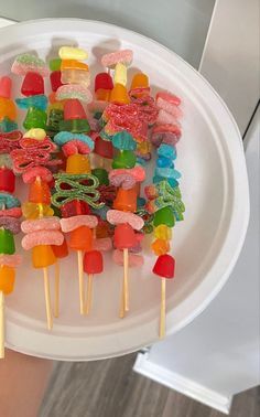 a white plate topped with lots of gummy bears on top of skewers