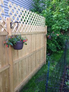 a wooden fence with potted plants hanging from it's sides and on the side