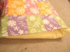 a dog laying on the floor next to a pillow with colorful squares and flower designs