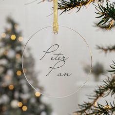 a glass ornament that says peter pan hanging from a christmas tree with lights in the background