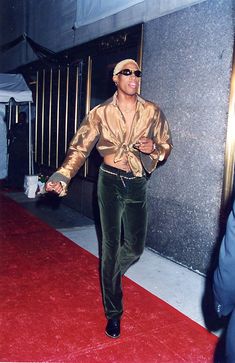 a man walking down a red carpet next to a tall building