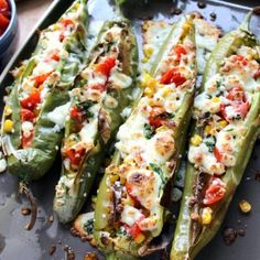 stuffed hatch green chiles on a tray with tomatoes and other vegetables in the background