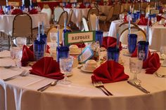 the table is set for an event with red napkins and silverware on it