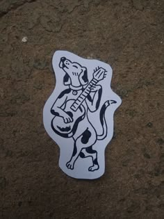 a sticker that is on the ground with a dog holding a guitar in it's mouth