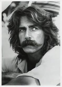 a black and white photo of a man with long hair and a moustache