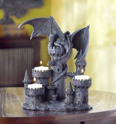 a dragon statue sitting on top of a table next to two candles in front of it