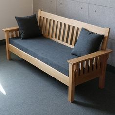 a wooden bench sitting in front of a wall with two pillows on top of it