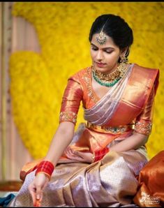 a woman sitting on the ground wearing a gold and red sari