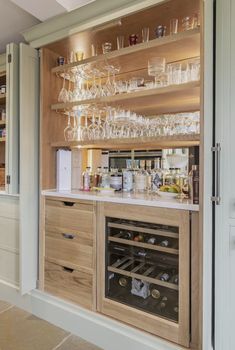 a wine bar with lots of glasses and bottles on the shelves in front of it