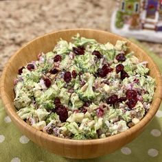 a wooden bowl filled with broccoli and cranberries