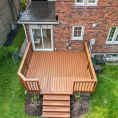 a wooden deck in front of a brick house