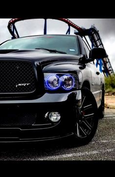 the front end of a black dodge ram truck with blue lights on it's headlight