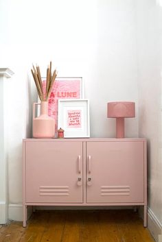 a pink cabinet with two doors and some pictures on the top shelf next to it