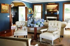 a living room with blue walls and white furniture in the centerpiece, along with an arched doorway leading to another room