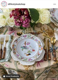 an image of a table setting with flowers and gold utensils in the center