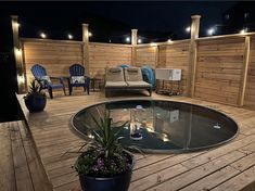 a deck with chairs and a table on it at night, lit up by string lights