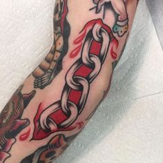 a man's arm with tattoos on it and a red chain around the wrist