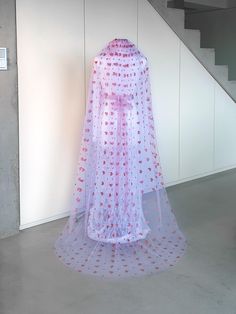 a white veil with red hearts on it sitting in front of a stair case next to a wall